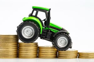 Bauern in der Landwirtschaft haben mit steigenden Kosten zu rechnen. Höhere Preies bei Futter, Dünger und Pflanzen. Traktor mit Münzen